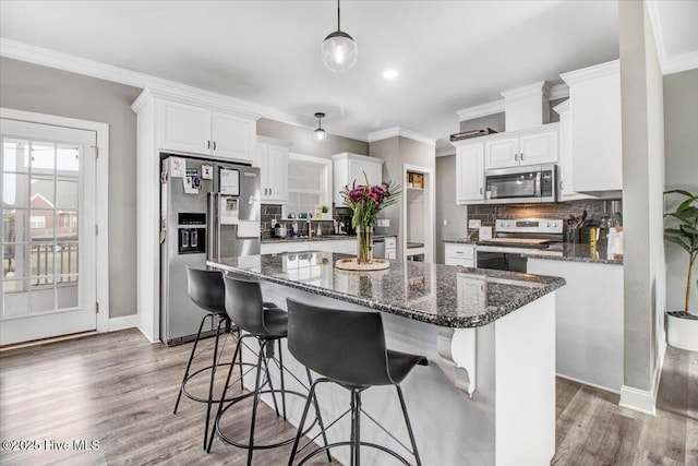 kitchen featuring backsplash, a kitchen island, crown molding, light wood-style floors, and stainless steel appliances