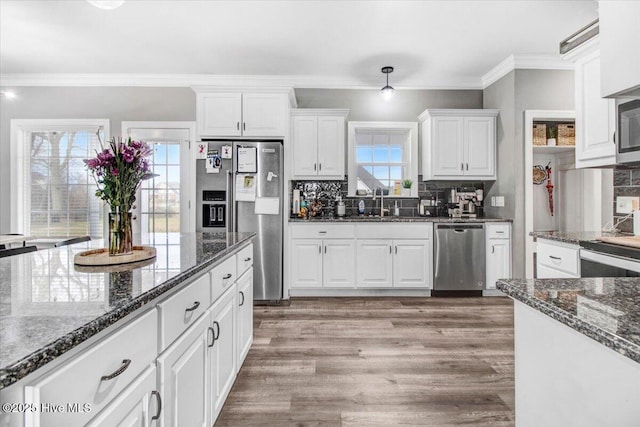 kitchen featuring a wealth of natural light, appliances with stainless steel finishes, and ornamental molding