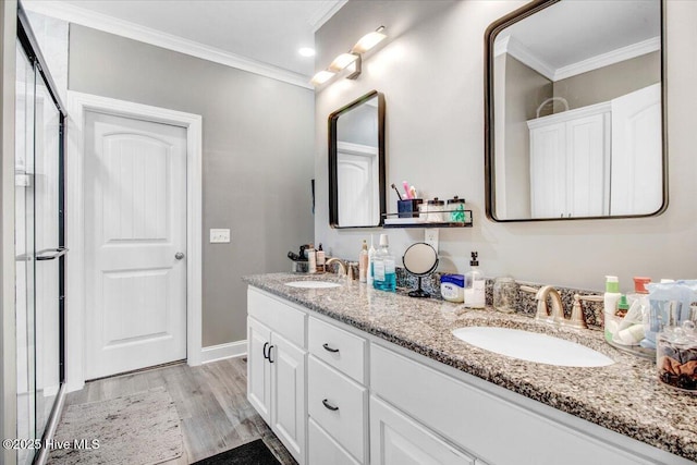 full bath with a sink, wood finished floors, ornamental molding, and double vanity