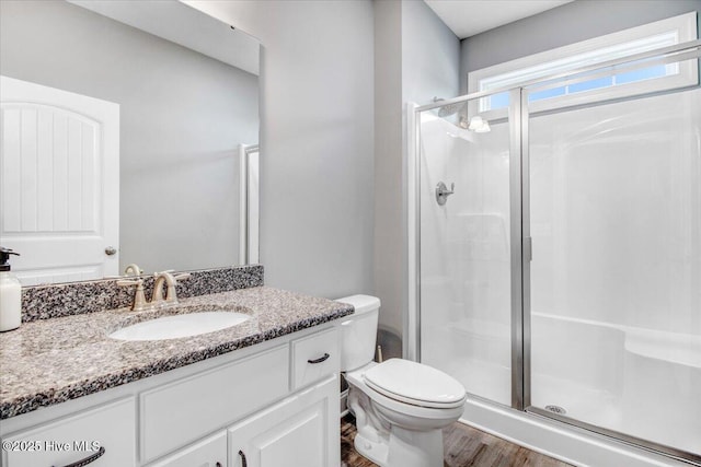 bathroom featuring vanity, a shower stall, toilet, and wood finished floors