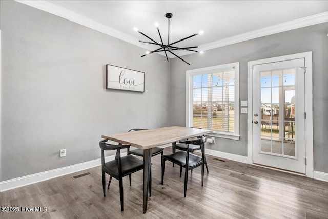 dining space with visible vents, baseboards, wood finished floors, and ornamental molding