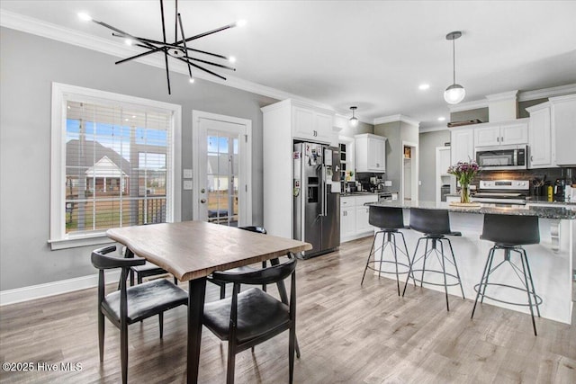 dining area featuring light wood-style flooring and ornamental molding