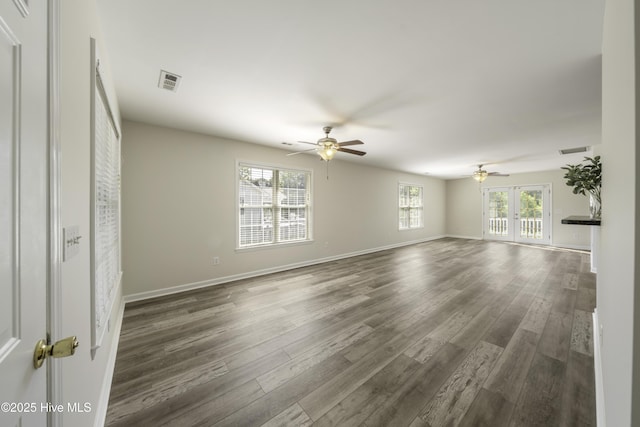 unfurnished living room with dark wood finished floors, a healthy amount of sunlight, and ceiling fan