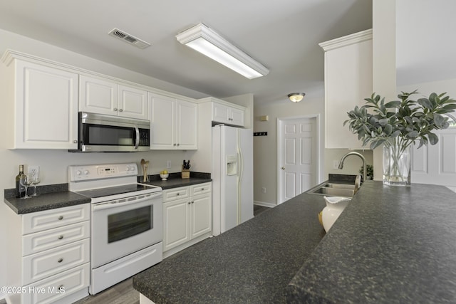 kitchen featuring white appliances, visible vents, a sink, white cabinetry, and dark countertops