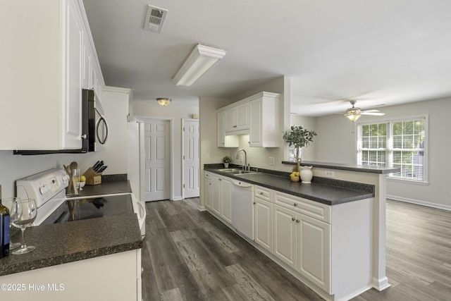 kitchen featuring dark countertops, a sink, electric stove, and white dishwasher