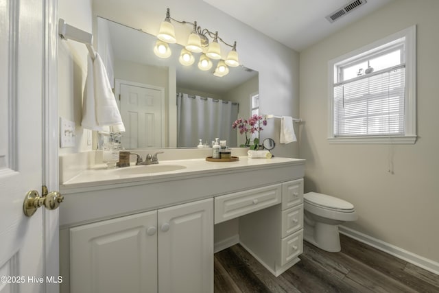 bathroom featuring vanity, wood finished floors, visible vents, baseboards, and toilet