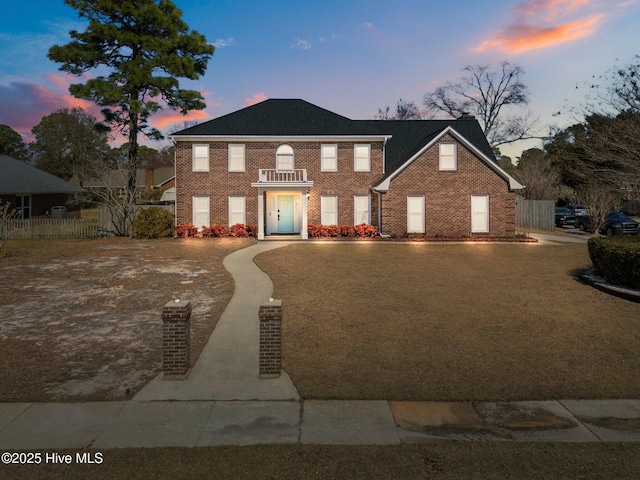 colonial house with brick siding, concrete driveway, and fence