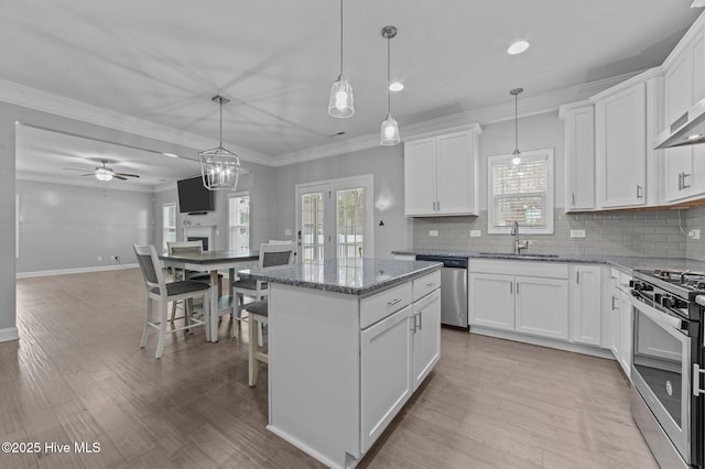 kitchen with tasteful backsplash, appliances with stainless steel finishes, crown molding, and a sink