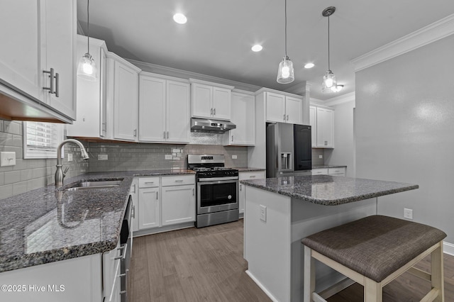 kitchen featuring stainless steel gas range oven, crown molding, under cabinet range hood, fridge with ice dispenser, and a sink