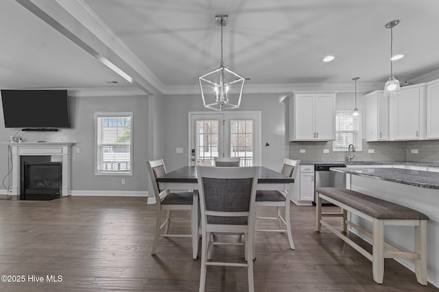 dining room featuring baseboards, a fireplace, dark wood-style flooring, and crown molding