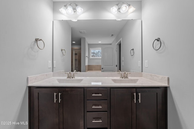 full bath with a sink, a shower with door, and double vanity