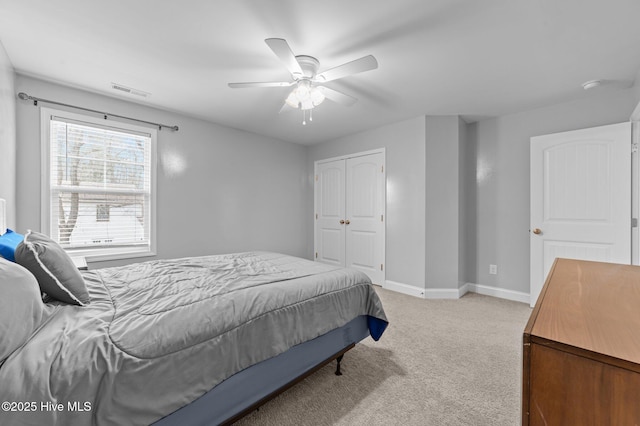 bedroom featuring a ceiling fan, visible vents, baseboards, a closet, and light carpet