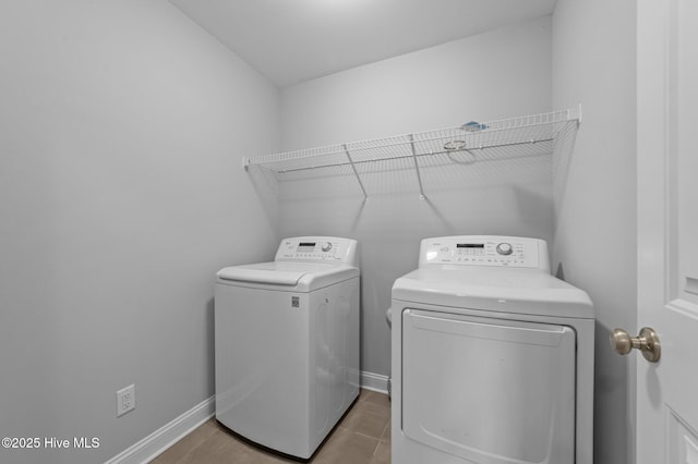 clothes washing area with laundry area, washing machine and dryer, and baseboards