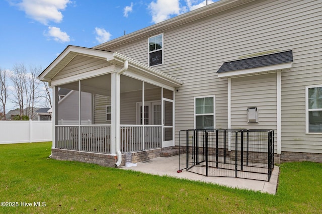 rear view of property with a patio, a lawn, fence, and a sunroom