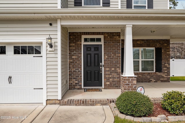 property entrance featuring a garage, brick siding, and covered porch