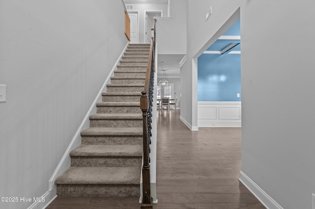 stairway featuring visible vents, baseboards, a chandelier, a wainscoted wall, and wood finished floors