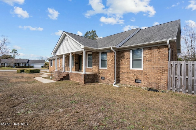 back of property with crawl space, brick siding, a yard, and fence