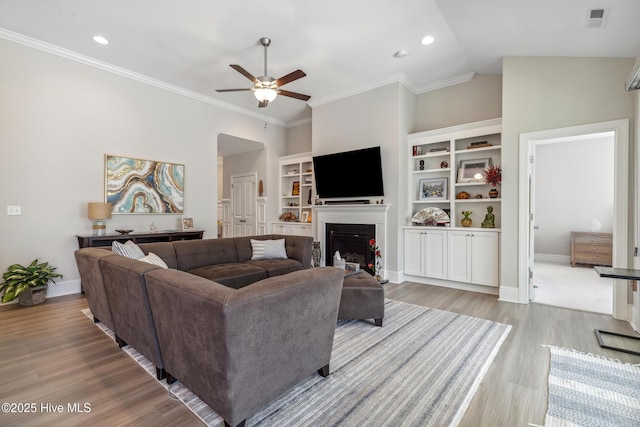 living area featuring visible vents, crown molding, lofted ceiling, and wood finished floors