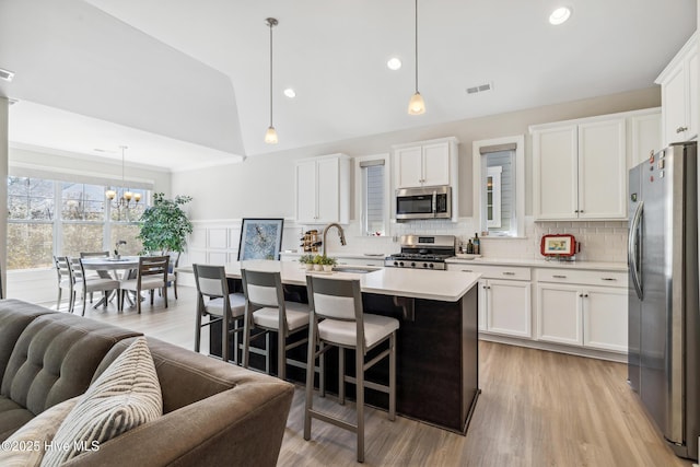 kitchen featuring a sink, stainless steel appliances, light countertops, white cabinetry, and open floor plan