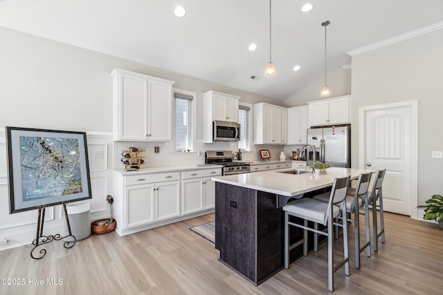 kitchen with backsplash, a breakfast bar area, white cabinets, stainless steel appliances, and a sink