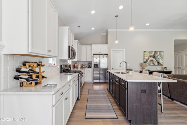 kitchen featuring tasteful backsplash, a breakfast bar, stainless steel appliances, white cabinetry, and a sink