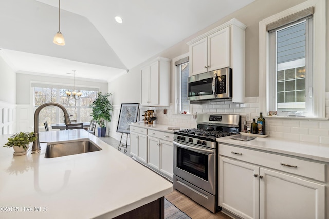 kitchen with tasteful backsplash, light countertops, lofted ceiling, stainless steel appliances, and a sink