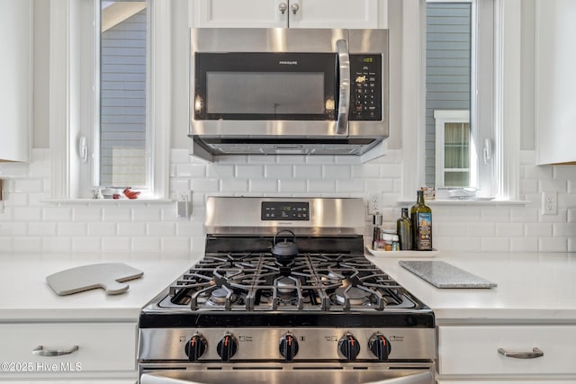 kitchen featuring decorative backsplash, light countertops, white cabinets, and stainless steel appliances