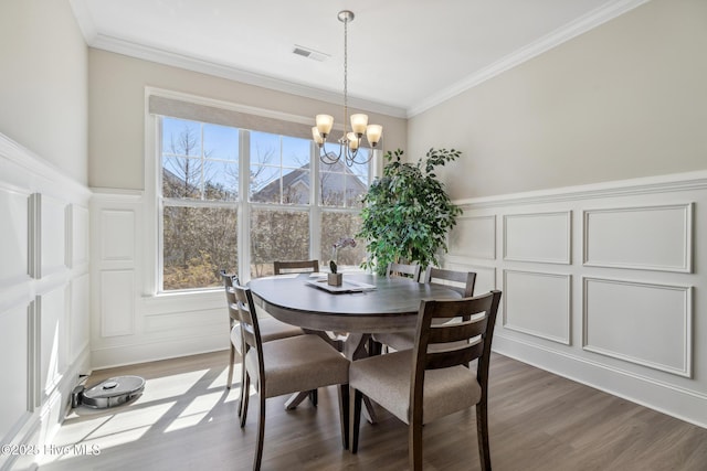 dining space with a chandelier, visible vents, a decorative wall, and wood finished floors