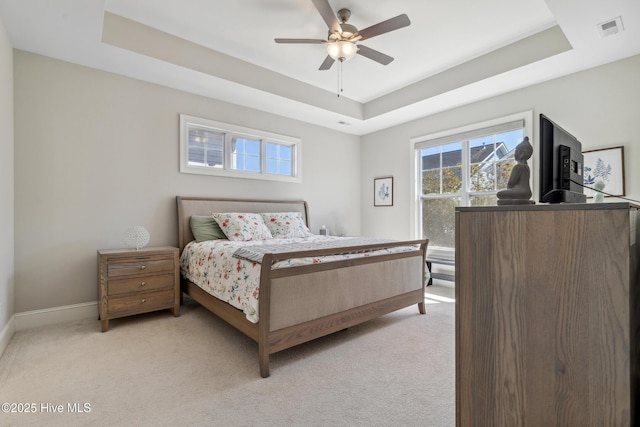 bedroom with a raised ceiling, visible vents, and light carpet