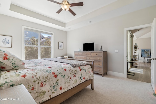 bedroom featuring visible vents, light carpet, a raised ceiling, a ceiling fan, and baseboards