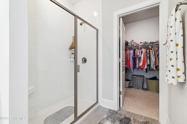 bathroom with tile patterned floors, a stall shower, and a walk in closet