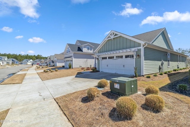 view of side of property featuring board and batten siding, an attached garage, driveway, and a shingled roof