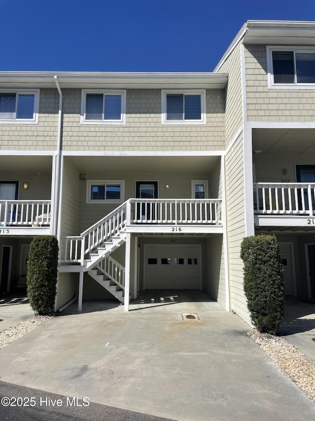 view of front of home with stairs, an attached garage, and driveway