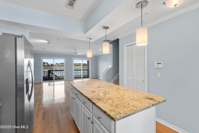 kitchen featuring stainless steel fridge, ornamental molding, light wood finished floors, and visible vents