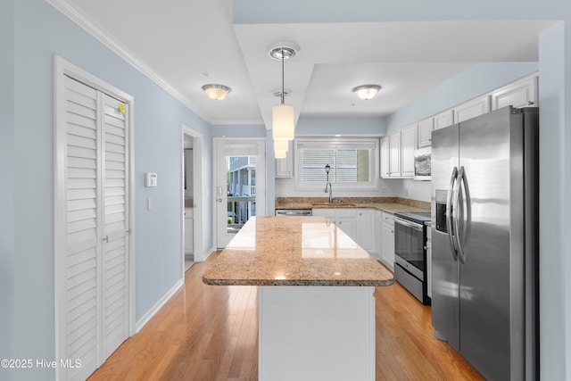 kitchen with crown molding, hanging light fixtures, a center island, stainless steel appliances, and white cabinetry