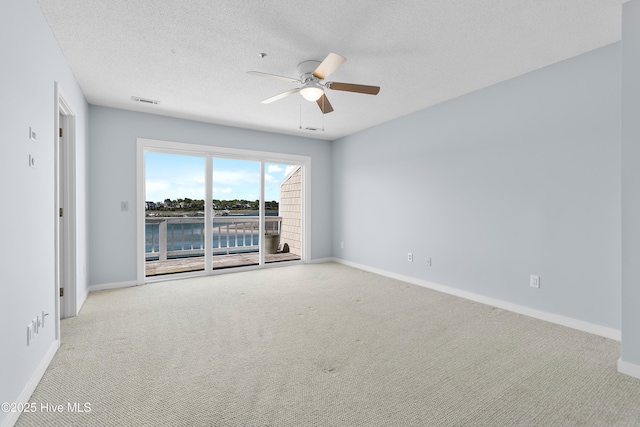 carpeted spare room with baseboards, ceiling fan, a textured ceiling, and visible vents