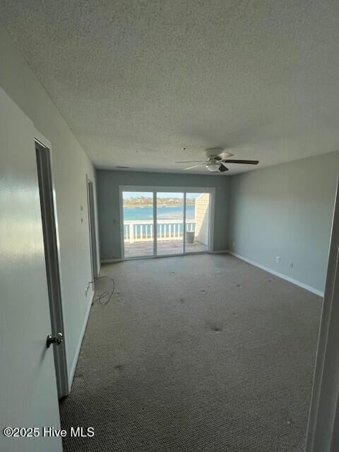 carpeted spare room featuring baseboards, a textured ceiling, and ceiling fan