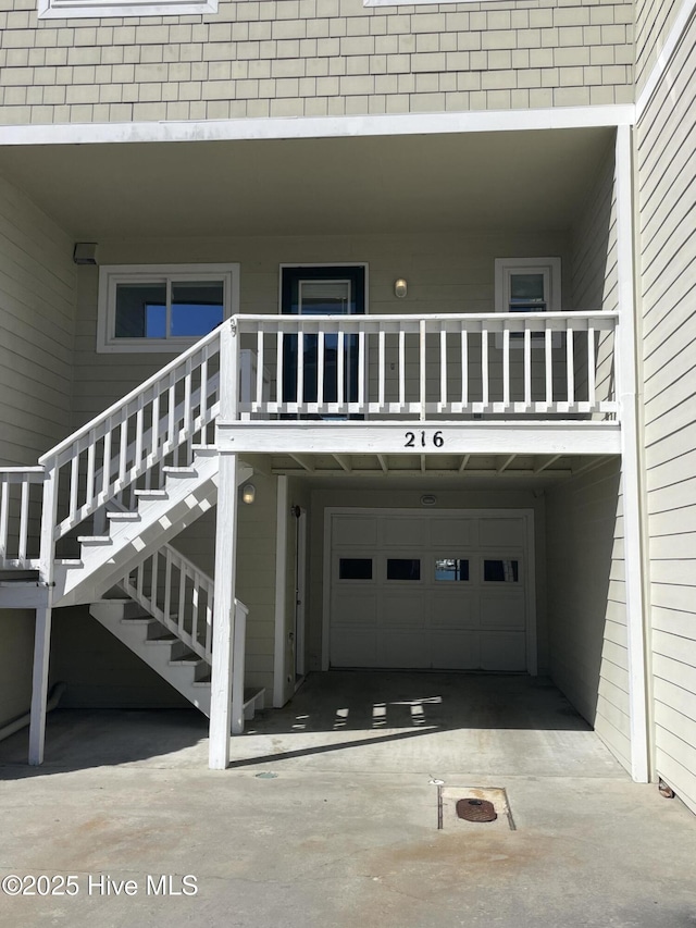 property entrance with an attached garage, concrete driveway, and a balcony