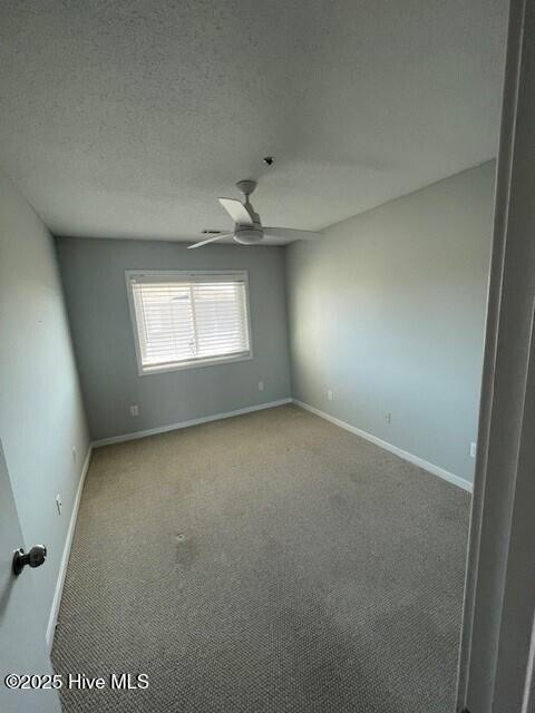 carpeted spare room with a ceiling fan, baseboards, and a textured ceiling