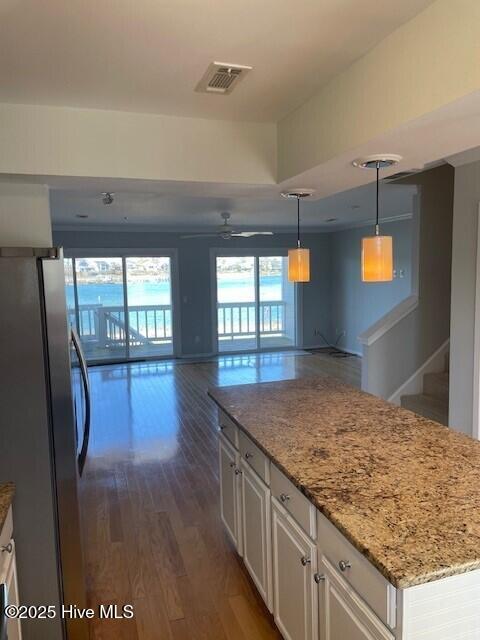 kitchen featuring visible vents, dark wood-style flooring, freestanding refrigerator, white cabinetry, and open floor plan