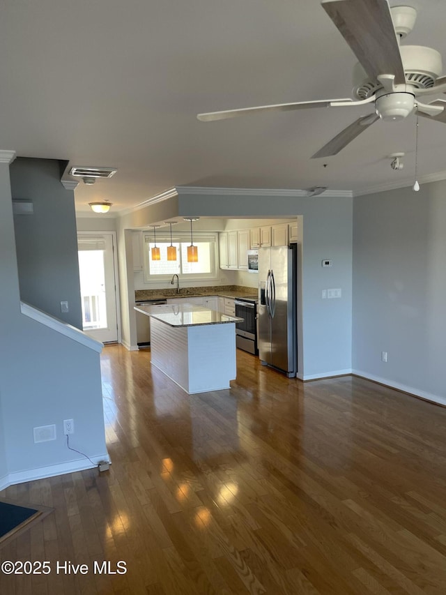 kitchen featuring ornamental molding, a kitchen island, stainless steel appliances, ceiling fan, and dark wood-style flooring