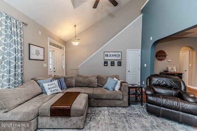 living room with ceiling fan, arched walkways, and high vaulted ceiling