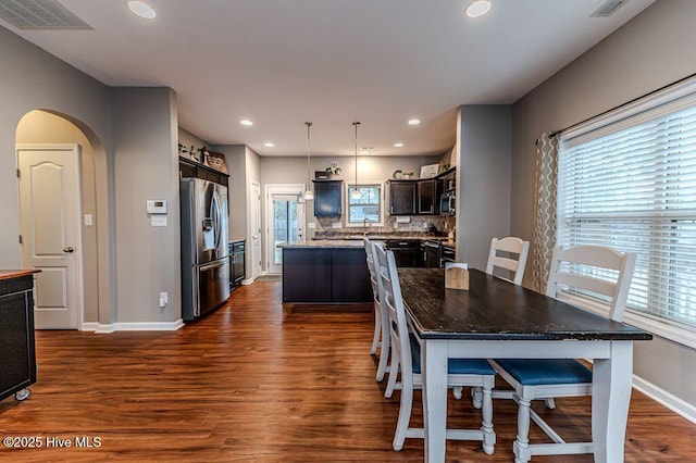 dining space with visible vents, arched walkways, baseboards, and dark wood-style flooring