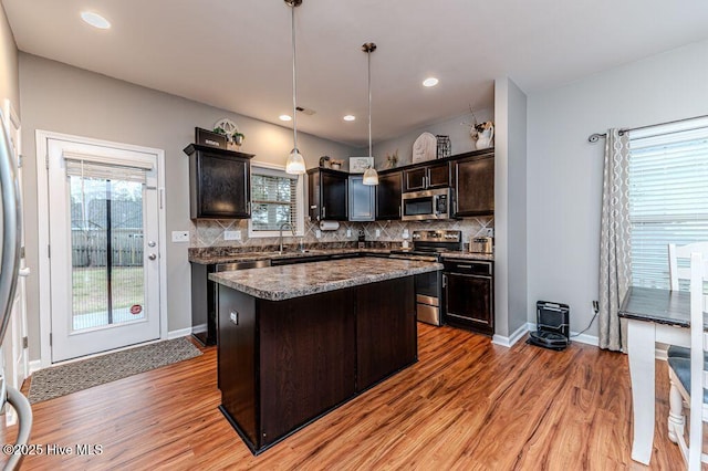 kitchen with backsplash, light wood finished floors, appliances with stainless steel finishes, and a sink