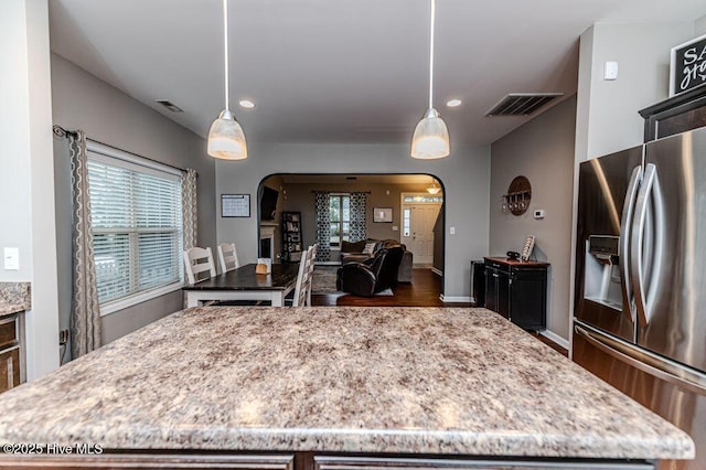 kitchen featuring visible vents, stainless steel fridge with ice dispenser, arched walkways, and a kitchen island