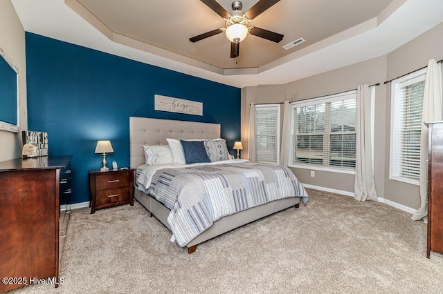 bedroom with visible vents, a tray ceiling, carpet floors, baseboards, and ceiling fan