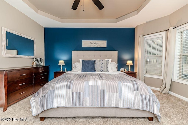 bedroom with a ceiling fan, a raised ceiling, carpet, and baseboards