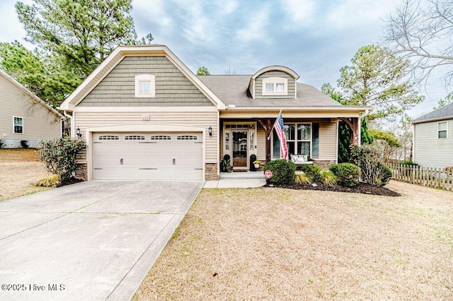 view of front of home featuring fence, driveway, covered porch, stone siding, and a garage