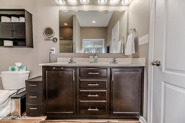 bathroom with a sink, toilet, and double vanity