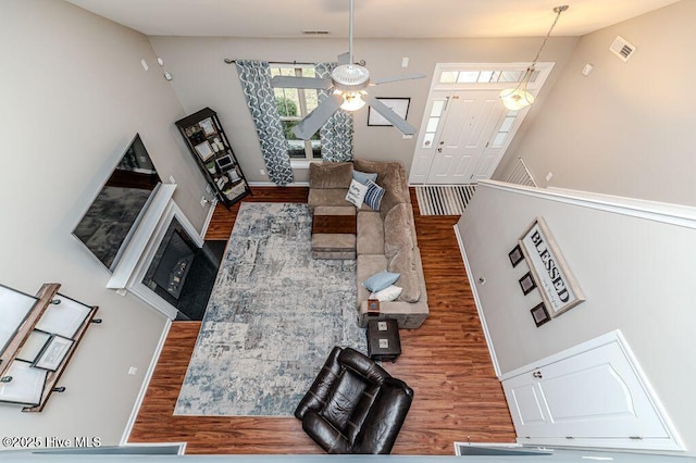 living area featuring a ceiling fan, wood finished floors, visible vents, and baseboards